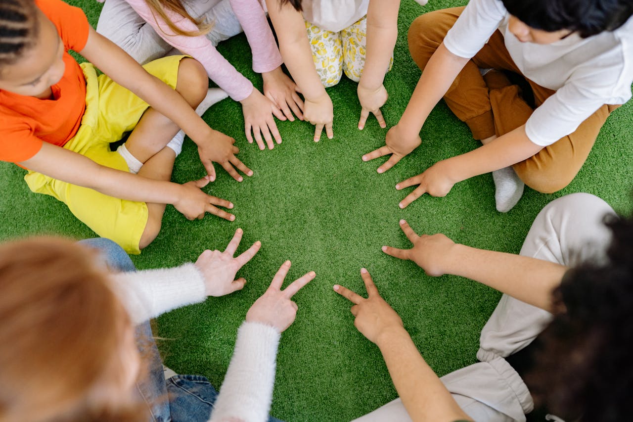 Children sitting in a circle playing fun team games on artificial grass.